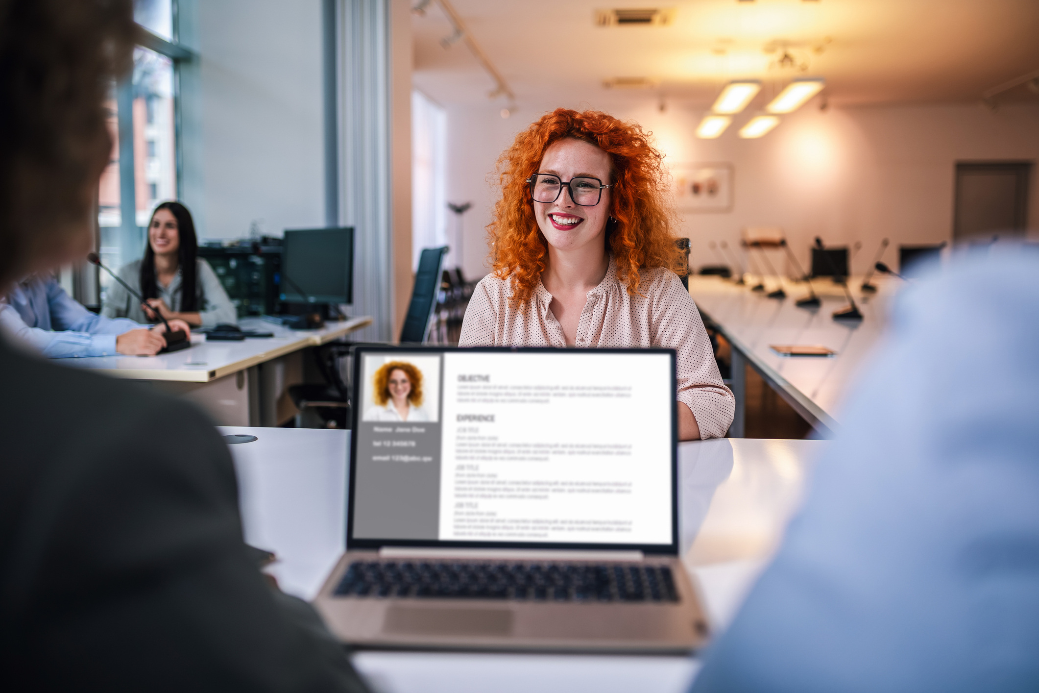 A redheaded woman is facing an interviewer. 